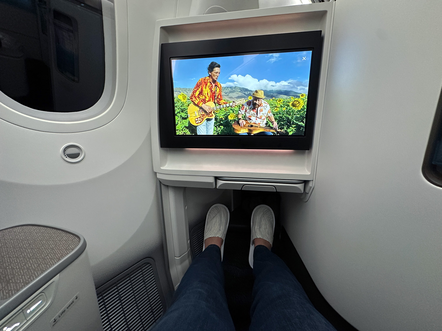 The author pictured wearing her slippers with her feat outstretched in the lie-flat seat.